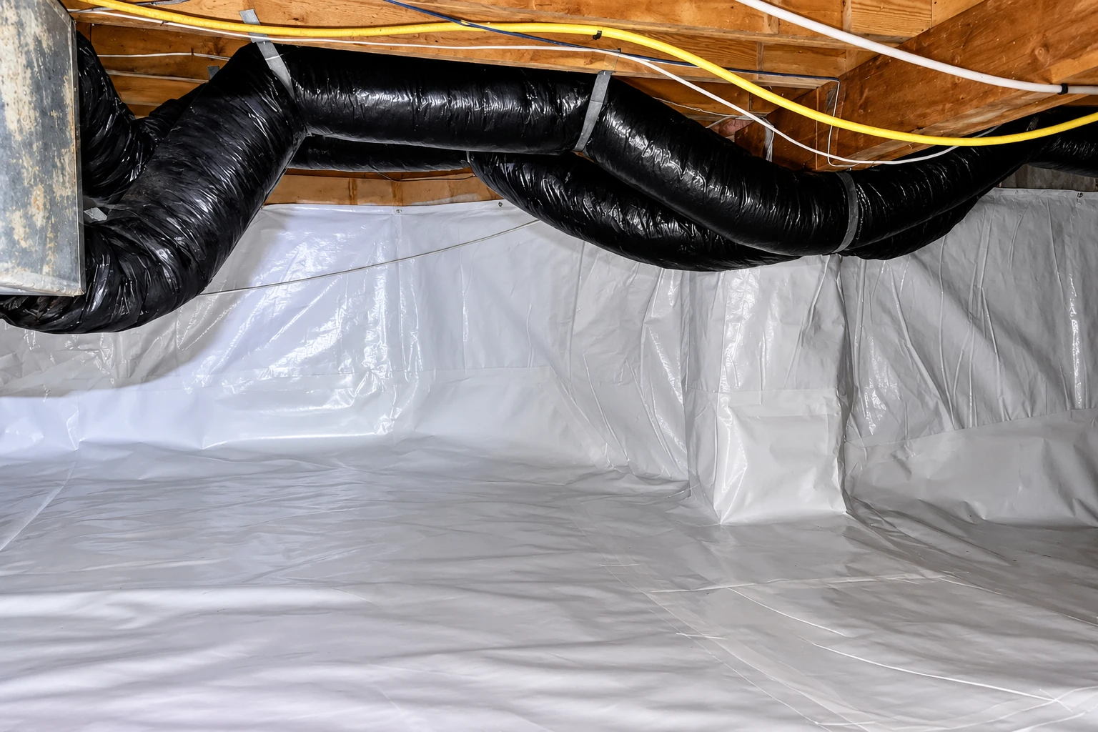 A crawl space has white plastic vapor barrier lining the ground and walls beneath exposed joists and a large black duct.
